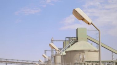 Çimento fabrikası. Ön planda, çimento üretiminde büyük olasılıkla fırın olan birkaç büyük silindirik yapı vardır. Fırınlar büyük, dönen fırınlardır, kireçtaşı ve diğer şeyleri ısıtırlar.
