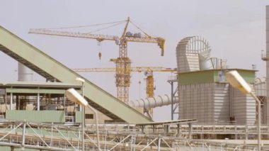 Çimento fabrikası. Ön planda, çimento üretiminde büyük olasılıkla fırın olan birkaç büyük silindirik yapı vardır. Fırınlar büyük, dönen fırınlardır, kireçtaşı ve diğer şeyleri ısıtırlar.