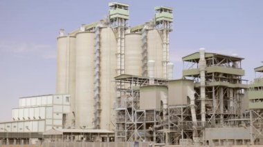 Çimento fabrikası. Ön planda, çimento üretiminde büyük olasılıkla fırın olan birkaç büyük silindirik yapı vardır. Fırınlar büyük, dönen fırınlardır, kireçtaşı ve diğer şeyleri ısıtırlar.