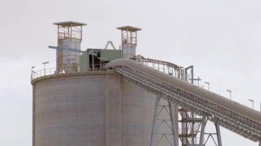 Çimento fabrikası. Ön planda, çimento üretiminde büyük olasılıkla fırın olan birkaç büyük silindirik yapı vardır. Fırınlar büyük, dönen fırınlardır, kireçtaşı ve diğer şeyleri ısıtırlar.