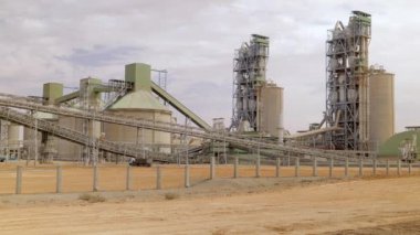 Çimento fabrikası. Ön planda, çimento üretiminde büyük olasılıkla fırın olan birkaç büyük silindirik yapı vardır. Fırınlar büyük, dönen fırınlardır, kireçtaşı ve diğer şeyleri ısıtırlar.