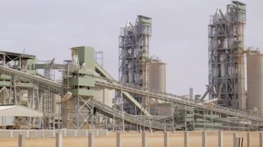 Çimento fabrikası. Ön planda, çimento üretiminde büyük olasılıkla fırın olan birkaç büyük silindirik yapı vardır. Fırınlar büyük, dönen fırınlardır, kireçtaşı ve diğer şeyleri ısıtırlar.