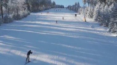 Dağdan inen kayakçılar, İHA manzaralı. Yüksek kaliteli 4K görüntüler büyüleyici hava manzarası kayakçıları zarifçe aşağı inen karlı yamaçları yakalar, arka planda zarif kavisler çizer.