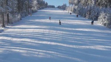 Dağdan inen kayakçılar, İHA manzaralı. Yüksek kaliteli 4K görüntüler büyüleyici hava manzarası kayakçıları zarifçe aşağı inen karlı yamaçları yakalar, arka planda zarif kavisler çizer.