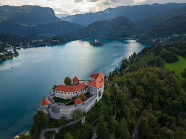 İHA uçuşu. Slovenya. Kanlı Kale. Bled Gölü. Altınızda Bled Gölü var, masmavi gökyüzünü yansıtan bir ayna ve yemyeşil dağlar. Uçurumun tepesinde bir ortaçağ başyapıtı olan Kanlı Kale yükseliyor.