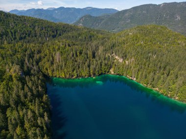 İHA uçuşu. İtalya 'daki Iago Inferiore di Fusine Gölü. Tekne. Altınızda gökyüzünün renklerini yansıtan büyüleyici bir göl var. Yüzeyi zümrüt yeşili bir renkle parıldıyor.