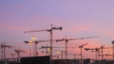 Günbatımında Suudi Arabistan 'daki mega inşaatta çalışan bir sürü vinç var. Videoda Suudi Arabistan 'da çok sayıda vinç siluetiyle büyük ölçekli bir inşaat sahası tasvir ediliyor.