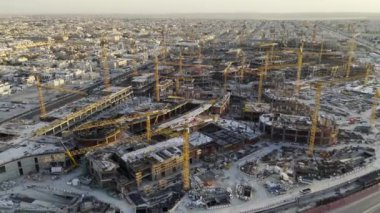 Gün batımında Suudi Arabistan 'ın Mega inşaatının insansız hava aracı görüntüsü. Bolca vinçle. Videoda Suudi Arabistan 'da çok sayıda vinç siluetiyle büyük ölçekli bir inşaat sahası tasvir ediliyor.