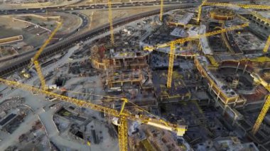 Gün batımında Suudi Arabistan 'ın Mega inşaatının insansız hava aracı görüntüsü. Bolca vinçle. Videoda Suudi Arabistan 'da çok sayıda vinç siluetiyle büyük ölçekli bir inşaat sahası tasvir ediliyor.