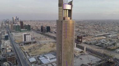 Aynalı gökdelen, Suudi Arabistan Riyad 'ın ortasında açık bir alan. Video, Suudi Arabistan, Riyad 'da çarpıcı bir gökdeleni gösteriyor. Önünde aynalı bir cephe ve açık bir alan var.
