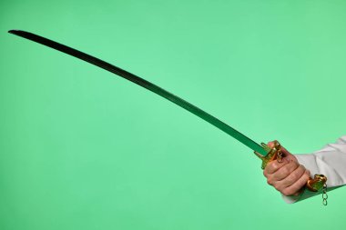 Traditional Saudi out-feet on chromakey. Arabian long saber - saif. It shows traditional Saudi attire against a chromakey green screen, commonly used in video production for ease of digital editing clipart