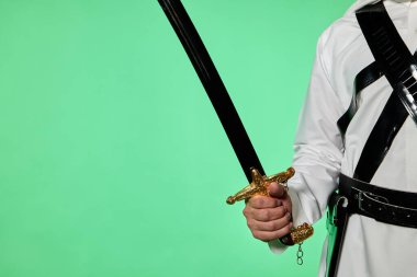 Geleneksel Suudi ayağının üzerinde kromakey. Arap uzun kılıcı - saif. Geleneksel Suudi kıyafetlerini kromakey yeşil ekrana karşı gösteriyor. Genellikle dijital kurguyu kolaylaştırmak için video yapımında kullanılır.