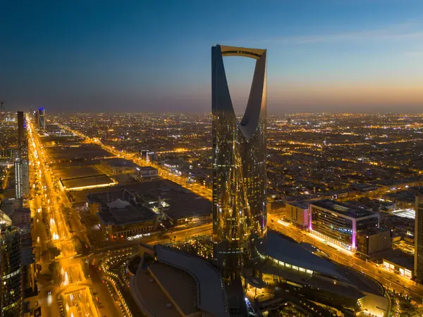 Suudi Arabistan, Riyad 'ın üzerinde zarif bir şekilde asılı duran, gün batımında görkemli Kraliyet Kulesi' ni çeken bir drone fotoğrafı. Şehir aşağıya doğru yayılıyor, mimarisinde modernliği yansıtıyor,