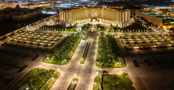 Fotoğraf, Suudi Arabistan 'ın Riyad kentindeki görkemli bir binanın, lüks bir otelin ya da sarayın muhteşem gece manzarasını çekiyor. Bina altın bir ışıkla aydınlatılıyor.
