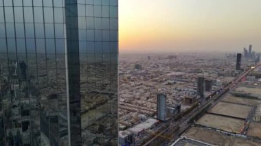 İnsansız uçak zarif bir şekilde Suudi Arabistan, Riyad üzerinde süzülerek görkemli Krallık Kulesi 'ni gün ışığında ele geçirdi. Gün doğumu. Şehir, mimarisinde modernliği yansıtırken, yerin altına yayılır.