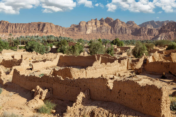 Ruins of AlUla Old Town Ancient Mud-Brick Village in Saudi Arabia. A breathtaking view of the ruins of AlUla Old Town, an ancient mud-brick village nestled within the dramatic rock formations and lush