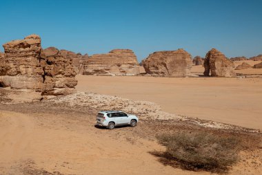 Alula 'daki Off-Road Adventure, Suudi Arabistan 4x4 SUV in the Desert. Güçlü bir 4x4 SUV, AlUlas kaya oluşumlarının dramatik arka planına karşı duruyor ve nihai çöl macerasını sergiliyor. AlUla, bir.