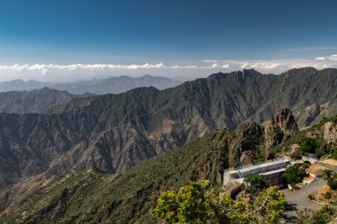 Suudi Arabistan, Abha 'nın nefes kesici dağ manzarası. Suudi Arabistan, Abha 'yı çevreleyen dağların büyüleyici panoramik görüntüsü. Yuvarlanan yeşil tepeler, dolambaçlı yollar ve sisli bulutlar