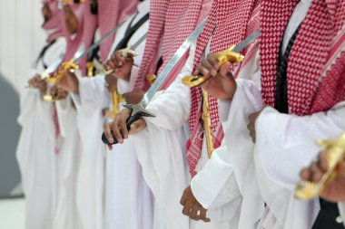 Geleneksel Suudi Arabistan Kılıç Dansı - Ardah Performans. Geleneksel Suudi Arabistan kıyafeti giymiş bir grup erkek, kültürel kılıç dansı Ardah 'ı sahneledi. Her katılımcı karmaşık bir şekilde...