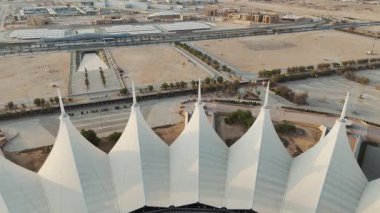 Riyad Stadyumu 'nun gündoğumunun hava görüntüsü. Güneş doğarken Suudi Arabistan 'ın Riyad kentindeki ikonik stadyumu gösteren sakin bir hava manzarası. Yapının eşsiz beyaz, çadırımsı çatısı.