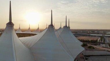 Riyad Stadyumu 'nun gündoğumunun hava görüntüsü. Güneş doğarken Suudi Arabistan 'ın Riyad kentindeki ikonik stadyumu gösteren sakin bir hava manzarası. Yapının eşsiz beyaz, çadırımsı çatısı.