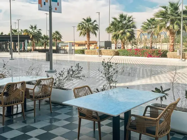 U-Walk Riyad 'da açık kafe koltuklar. Suudi Arabistan, Riyad 'da U-Walk' da şık bir açık hava oturma alanı. Minimalist mermer masalar, dokuma sandalyeler ve kareli zemin sunar.