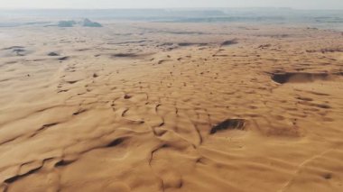 Suudi kum tepelerinin Sonsuz Çöl Ucu İHA videosu. Suudi Arabistan 'daki uçsuz bucaksız altın kum tepelerini gösteren çarpıcı bir insansız hava aracı videosu. Havadaki görüntüler rüzgâr şeklindeki büyüleyici desenleri ortaya çıkarıyor.