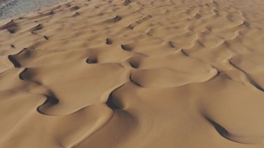 Suudi kum tepelerinin Sonsuz Çöl Ucu İHA videosu. Suudi Arabistan 'daki uçsuz bucaksız altın kum tepelerini gösteren çarpıcı bir insansız hava aracı videosu. Havadaki görüntüler rüzgâr şeklindeki büyüleyici desenleri ortaya çıkarıyor.
