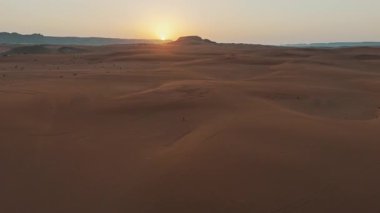 Suudi Çölü 'nde Gündoğumu Drone tarafından yakalandı. Yükselen güneşin altın ışınları bu nefes kesici hava manzarasında Suudi çölünün kayan kumullarını aydınlatıyor. Manzaranın pürüzsüz kıvrımları