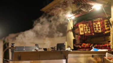 Çöl Kampı Mutfağı KSA. Gece Suudi Çölü 'nde otantik kamp mutfağı kurulumu. Geleneksel yastıklar, ocaklar ve yemek malzemeleri çöl yaşamı için sıcak ve davetkar bir sahne oluşturur. Yüksek