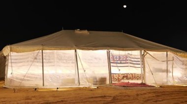 KSA 'da geleneksel bir Bedevi gece kampı. Suudi Arabistan çölündeki geleneksel bir Bedevi kampında huzurlu bir gece sahnesi. Fenerler yavaşça parıldıyor ve çekici bir Arap atmosferi yaratıyorlar.