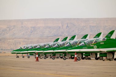Suudi Şahinler KSA Hava Gösterisinde. Suudi Arabistan Krallığı 'ndaki bir hava gösterisinde çarpıcı bir çöl zeminine karşı kalkışa hazır Suudi Hawks uçaklarının güçlü bir dizilişi.