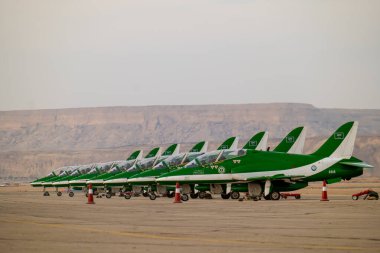 Suudi Şahinler KSA Hava Gösterisinde. Suudi Arabistan Krallığı 'ndaki bir hava gösterisinde çarpıcı bir çöl zeminine karşı kalkışa hazır Suudi Hawks uçaklarının güçlü bir dizilişi.