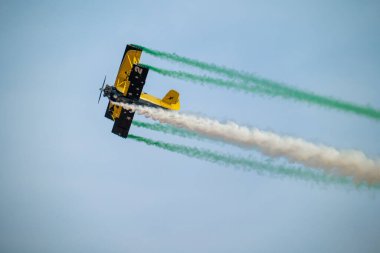 Wingwalker KSA Hava Gösterisi 'nde Suudi Çölü Havacılık Daring' in üstünde uçuyor. Korkusuz bir kanat yürüyüşçüsü, bir havacılık gösterisi sırasında çölde süzülen klasik sarı bir çift kanatlı uçağın tepesinde nefes kesici bir gösteri sergiliyor.