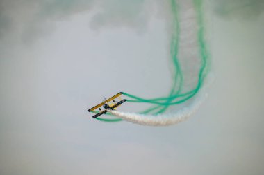Wingwalker KSA Hava Gösterisi 'nde Suudi Çölü Havacılık Daring' in üstünde uçuyor. Korkusuz bir kanat yürüyüşçüsü, bir havacılık gösterisi sırasında çölde süzülen klasik sarı bir çift kanatlı uçağın tepesinde nefes kesici bir gösteri sergiliyor.