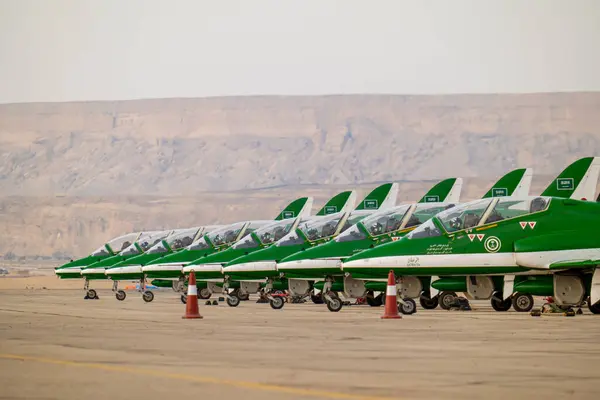 Suudi Şahinler KSA Hava Gösterisinde. Suudi Arabistan Krallığı 'ndaki bir hava gösterisinde çarpıcı bir çöl zeminine karşı kalkışa hazır Suudi Hawks uçaklarının güçlü bir dizilişi.