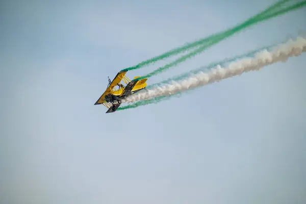 Wingwalker KSA Hava Gösterisi 'nde Suudi Çölü Havacılık Daring' in üstünde uçuyor. Korkusuz bir kanat yürüyüşçüsü, bir havacılık gösterisi sırasında çölde süzülen klasik sarı bir çift kanatlı uçağın tepesinde nefes kesici bir gösteri sergiliyor.
