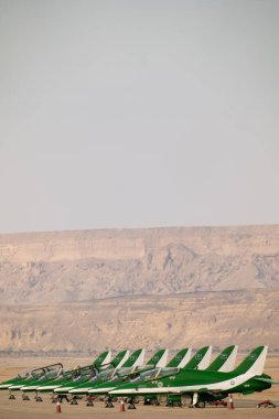Suudi Şahinler KSA Hava Gösterisinde. Suudi Arabistan Krallığı 'ndaki bir hava gösterisinde çarpıcı bir çöl zeminine karşı kalkışa hazır Suudi Hawks uçaklarının güçlü bir dizilişi.