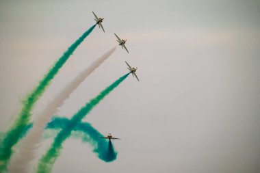 Suudi Şahinler Hassas Uçuş 'ta. Suudi Hawks 'ın Suudi Arabistan' daki bir uçuş gösterisi sırasında canlı yeşil ve beyaz duman izleriyle senkronize manevralar sergilediği hava gösterisi. Çarpıcı bir görüntü.