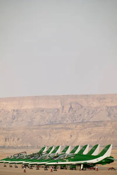 Suudi Şahinler KSA Hava Gösterisinde. Suudi Arabistan Krallığı 'ndaki bir hava gösterisinde çarpıcı bir çöl zeminine karşı kalkışa hazır Suudi Hawks uçaklarının güçlü bir dizilişi.