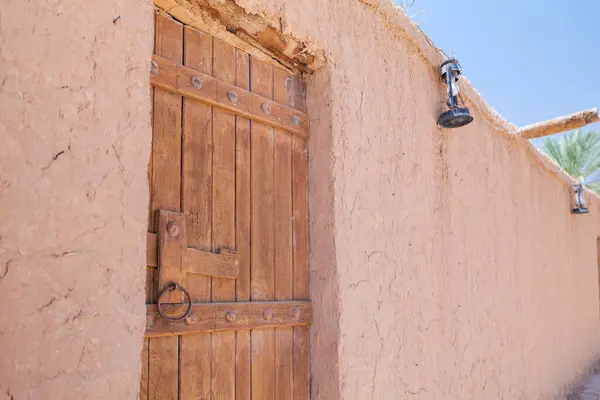 Suudi Arabistan 'daki Mud House' da geleneksel tahta kapı. Suudi Arabistan 'da, parlak mavi gökyüzü ve güneş ışığı altında, çamur tuğlalı bir evin metal detaylarıyla geleneksel ahşap kapısının yakın görüntüsü. Yüksek kalite