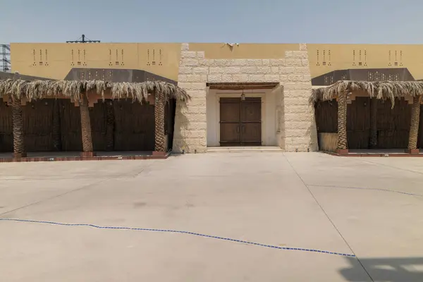 Bulvar 'daki geleneksel Suudi mimari ve avlusu. Geleneksel Suudi Arabistan mimarisinin sergilendiği, duvarları yerel taşlardan yapılmış ve detaylı ahşap bir binanın geniş bir görüntüsü.