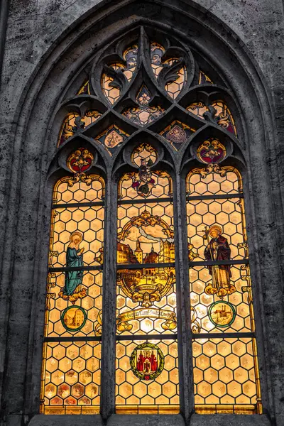 Münih Belediye Binası 'ndaki Gotik Lekeli Cam Pencere. Almanya 'nın Münih kentindeki Neue Rathaus Yeni Şehir Salonu' ndaki gotik vitraylı pencerenin yakın çekimi. Pencerede dini figürler, armalar yer alıyor.