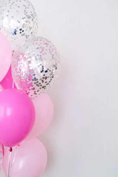 A bundle of pink and transparent air balloons with silver confetti, copy space for your text, tender pastel colors for a girlish party
