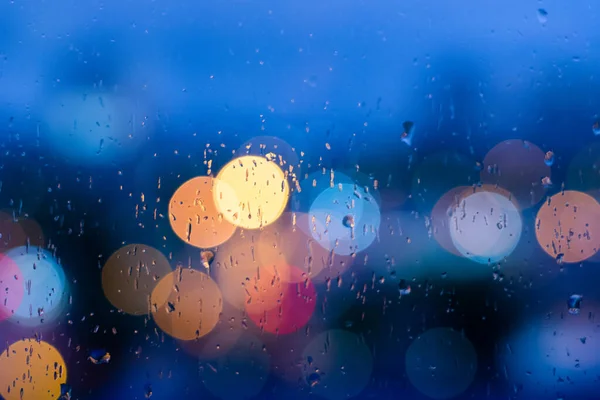 蓝色玻璃背景的雨滴 城市街灯分散焦点 抽象黄昏夜晚城市背景 — 图库照片