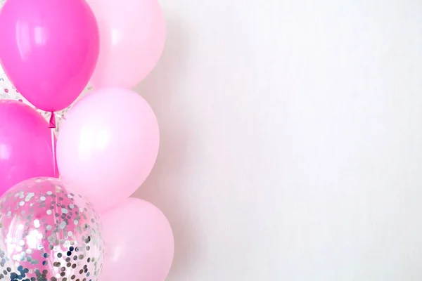 A bundle of pink and transparent air balloons with silver confetti, copy space for your text, tender pastel colors for a girlish party