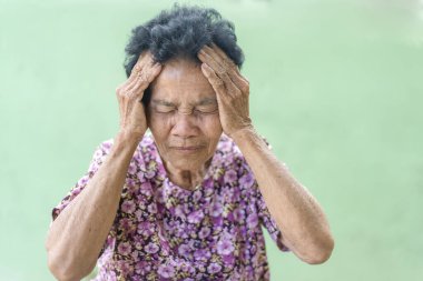 Senior black-haired woman touching head with hand with painful expression because of headache. Mature woman suffering from headache at home. Health care concept