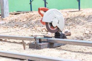 Elektrikli demir kesici yerdeki demiri kesti. Evin zemin katında inşaat halindeki eski paslı testere makinesi. Sert materyalleri kesmek için elektrikli makine