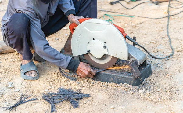 Stock image Man's hand using iron cutter in the workplace, fastening iron canopy frame with spark. Worker cutting steel with electric iron cutter. Steel cutter grinder cutting iron pipe with bright sparks.