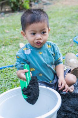 Little child shovels soil into pots to prepare plants for planting. Toddler boy digging soil for planting to Mother's little helper. Gardening. Hobbies at home horticulture. Leisure activities concept